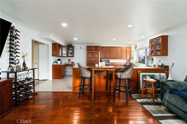 kitchen featuring glass insert cabinets, recessed lighting, ornamental molding, and wood finished floors