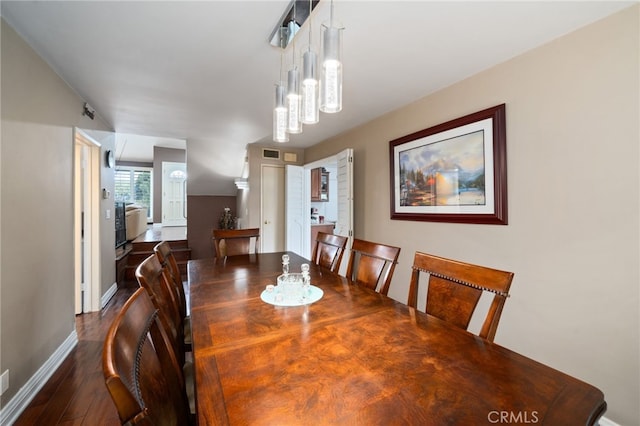 dining space featuring dark wood-style floors, a notable chandelier, and baseboards