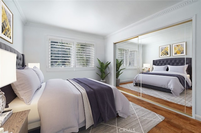 bedroom featuring a closet, crown molding, baseboards, and wood finished floors