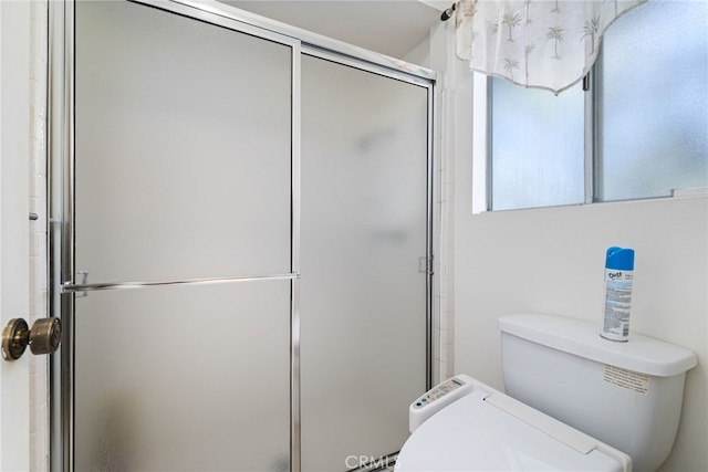 full bathroom featuring a wealth of natural light, a shower with shower door, and toilet