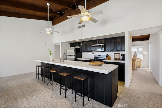 kitchen with dark cabinets, visible vents, a kitchen breakfast bar, light countertops, and appliances with stainless steel finishes