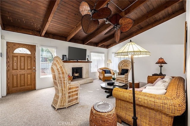 living room featuring a warm lit fireplace, ceiling fan, wood ceiling, vaulted ceiling with beams, and carpet