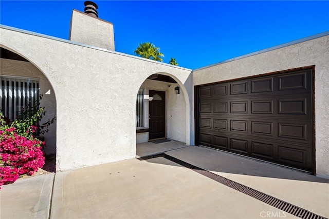 entrance to property with a chimney and stucco siding