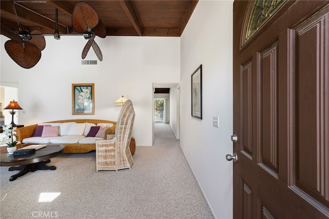 carpeted living room featuring wooden ceiling, visible vents, beamed ceiling, and a high ceiling