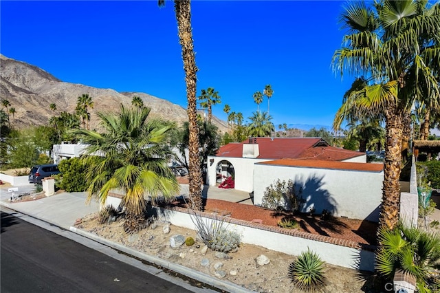 view of front of property with a fenced front yard, a mountain view, and stucco siding