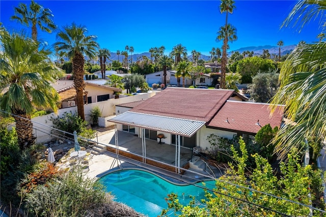 outdoor pool with a patio area, fence, and a mountain view