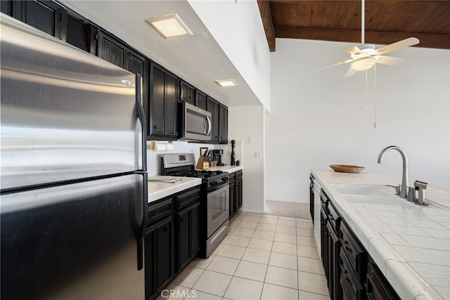 kitchen featuring tile countertops, stainless steel appliances, dark cabinetry, and light tile patterned floors