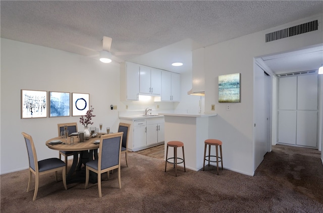 interior space featuring ceiling fan, dark colored carpet, a textured ceiling, and visible vents