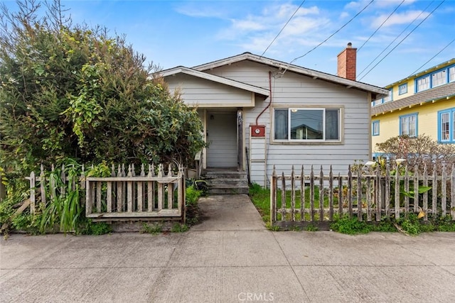 bungalow-style house featuring a fenced front yard and a chimney