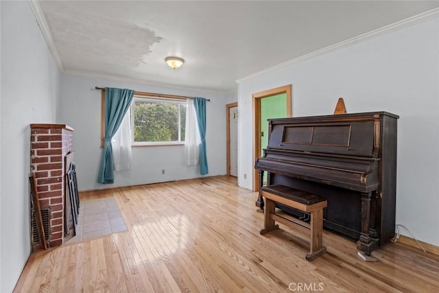 sitting room with crown molding, light wood finished floors, and a fireplace