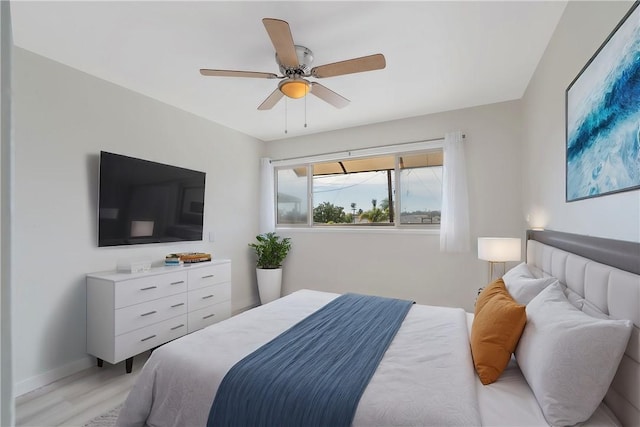 bedroom with baseboards, light wood-style floors, and a ceiling fan