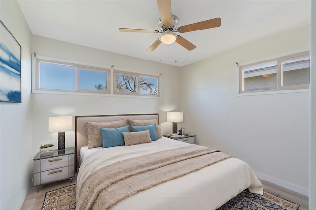 bedroom featuring light wood-type flooring, baseboards, and ceiling fan