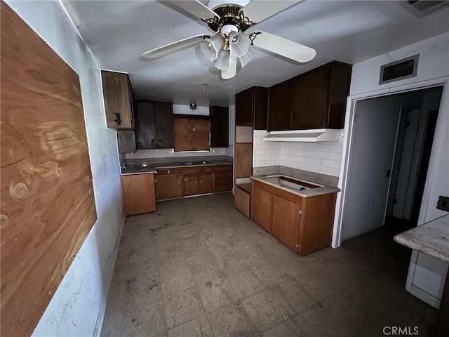 kitchen with tasteful backsplash, visible vents, under cabinet range hood, and light floors