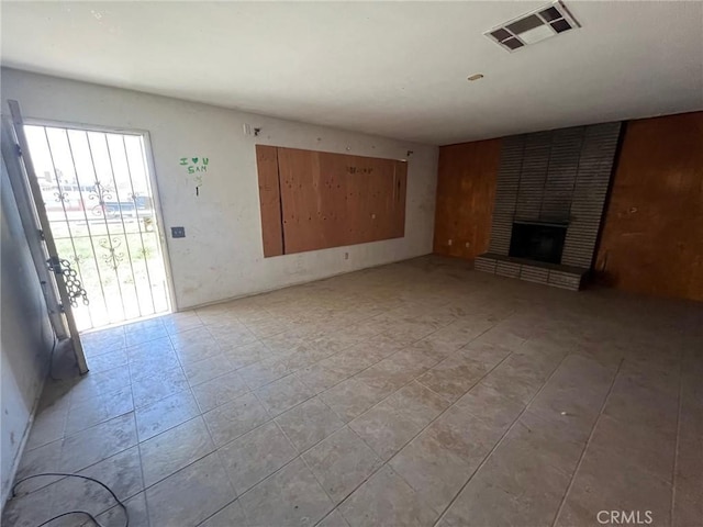 unfurnished living room with a brick fireplace and visible vents