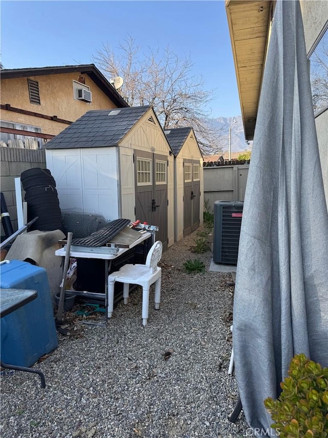 exterior space featuring an outdoor structure, cooling unit, fence, and a storage shed