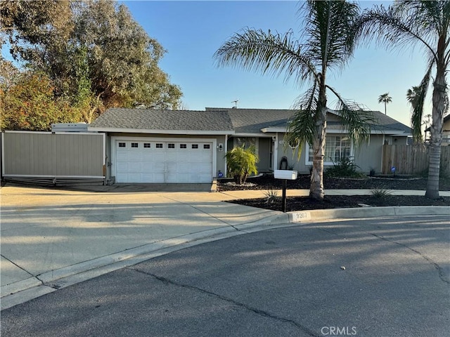 ranch-style house with a garage, driveway, and fence