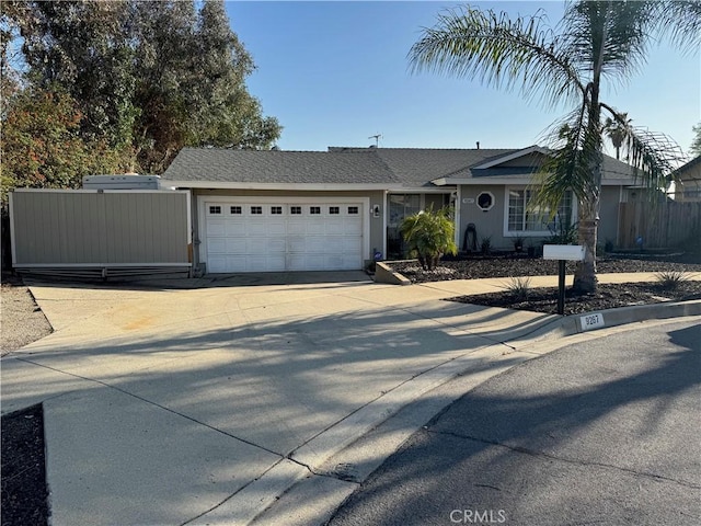 ranch-style home with a garage, concrete driveway, fence, and stucco siding