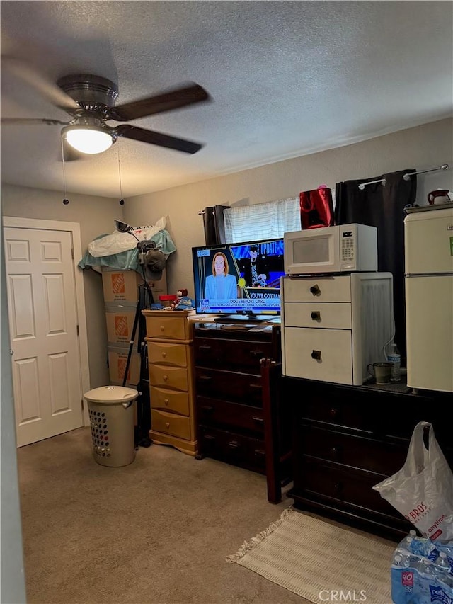 bedroom featuring light carpet, ceiling fan, a textured ceiling, and refrigerator