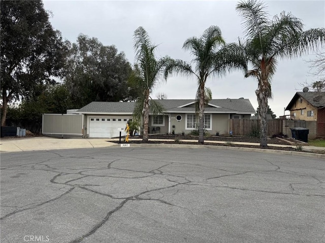 view of front of home with a garage, concrete driveway, and fence