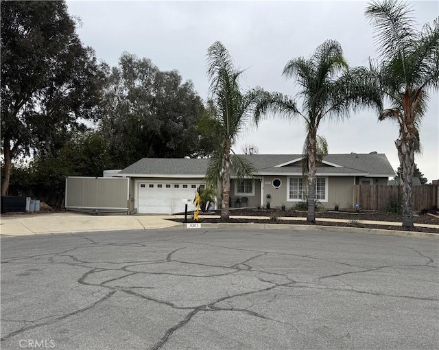 ranch-style home featuring concrete driveway, an attached garage, and fence