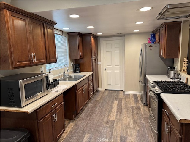 kitchen with dark wood-style floors, appliances with stainless steel finishes, light countertops, a sink, and recessed lighting