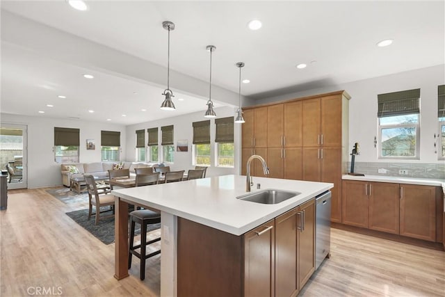 kitchen featuring light countertops, a sink, decorative light fixtures, and dishwasher