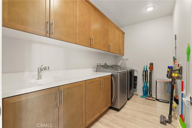 laundry room featuring recessed lighting, cabinet space, light wood-style flooring, a sink, and washer and dryer