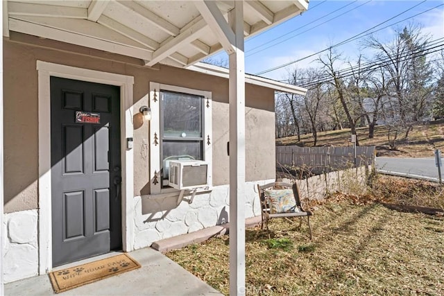 view of exterior entry with fence and stucco siding