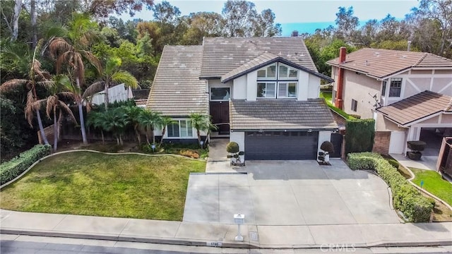 view of front of house with an attached garage, driveway, a tile roof, and a front yard