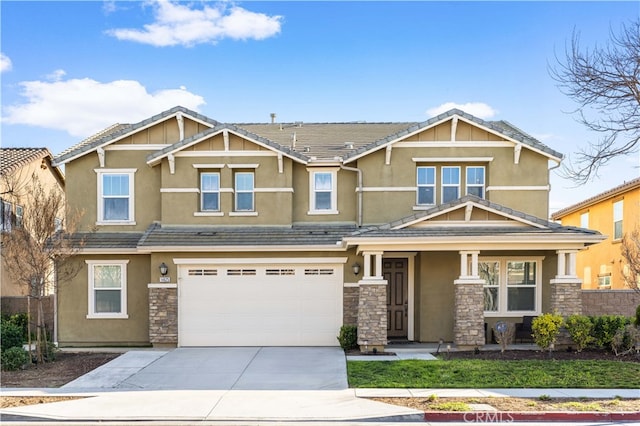 view of front of property featuring a garage, concrete driveway, stone siding, a tiled roof, and stucco siding