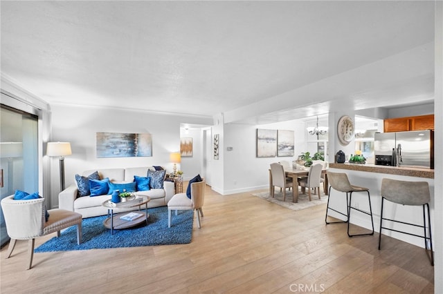 living room with light wood finished floors, baseboards, and an inviting chandelier