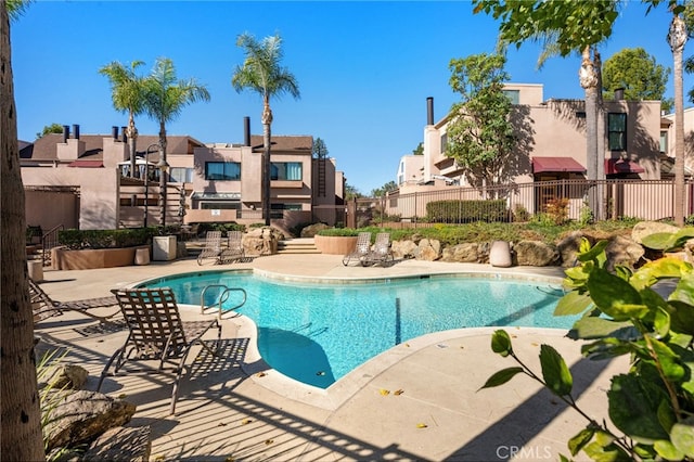 pool with a residential view, fence, and a patio