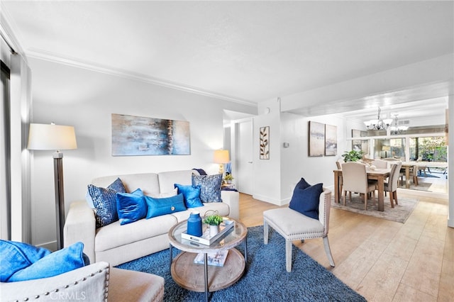 living room with a chandelier, ornamental molding, light wood-type flooring, and baseboards