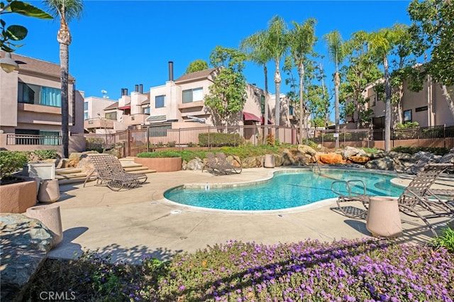 community pool featuring a patio, fence, and a residential view