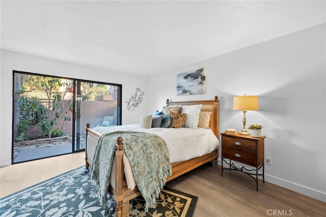 bedroom with access to outside, baseboards, and wood finished floors