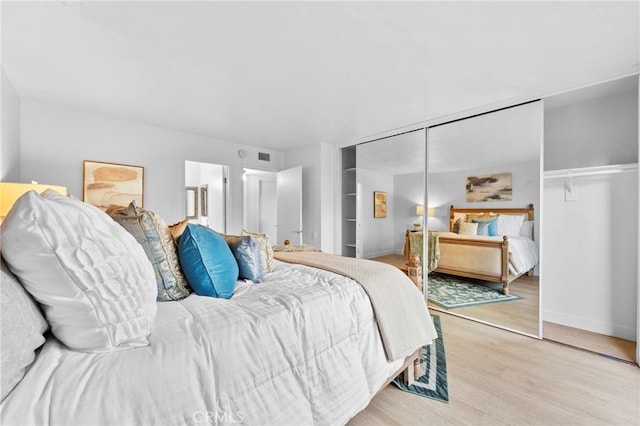 bedroom with connected bathroom, light wood-style flooring, visible vents, baseboards, and a closet