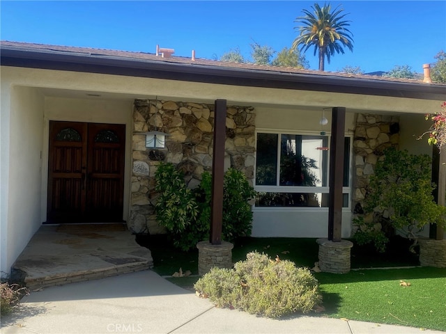 entrance to property with stone siding and a porch