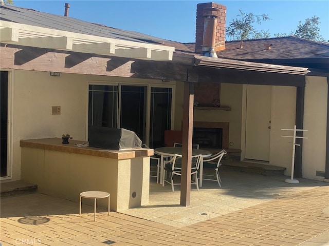 rear view of house with outdoor dining space, a patio, area for grilling, and stucco siding