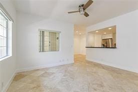 unfurnished living room featuring baseboards and a ceiling fan