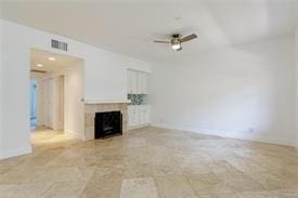 unfurnished living room with baseboards, a fireplace, visible vents, and a ceiling fan