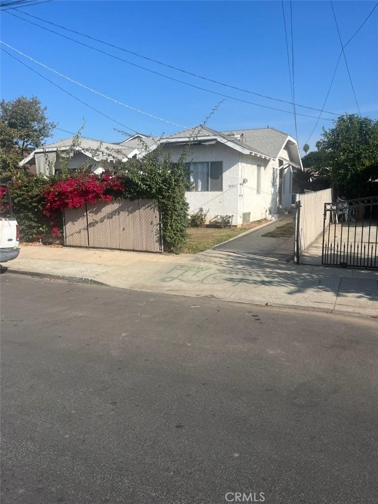 view of front of house with fence, a gate, and stucco siding