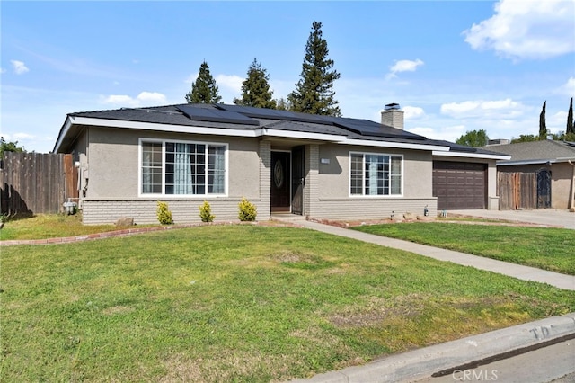 single story home featuring a garage, brick siding, fence, roof mounted solar panels, and a front yard