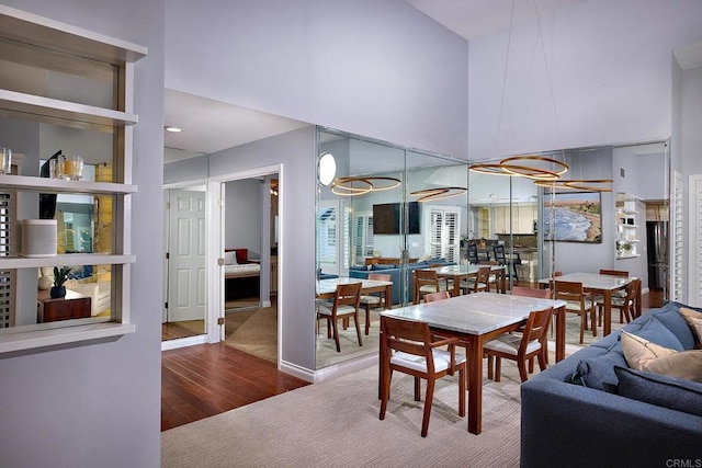 dining room with wood finished floors and a towering ceiling