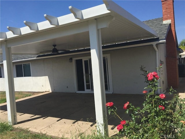 rear view of house with a patio area, stucco siding, ceiling fan, and roof with shingles