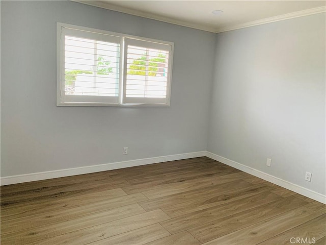 empty room featuring ornamental molding, baseboards, and wood finished floors