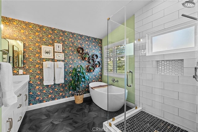 bathroom with a freestanding bath, a shower stall, vanity, baseboards, and wallpapered walls