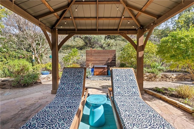 view of patio / terrace with an outdoor fireplace, fence, and a gazebo