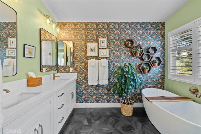 full bath featuring baseboards, a sink, and a freestanding bath