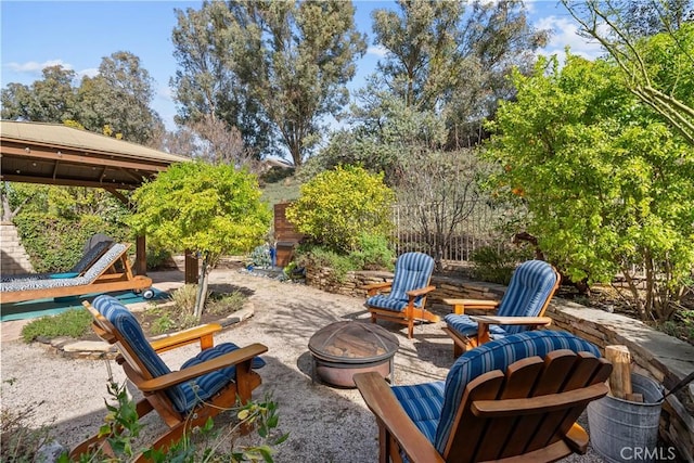 view of patio / terrace featuring fence, a fire pit, and a gazebo