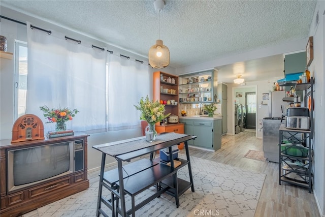 dining area with a healthy amount of sunlight, light wood finished floors, and a textured ceiling